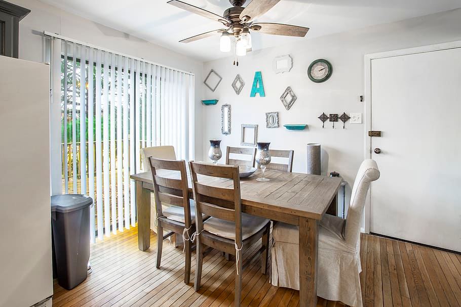 Ceiling fan with light fixture above a sunlit dining table