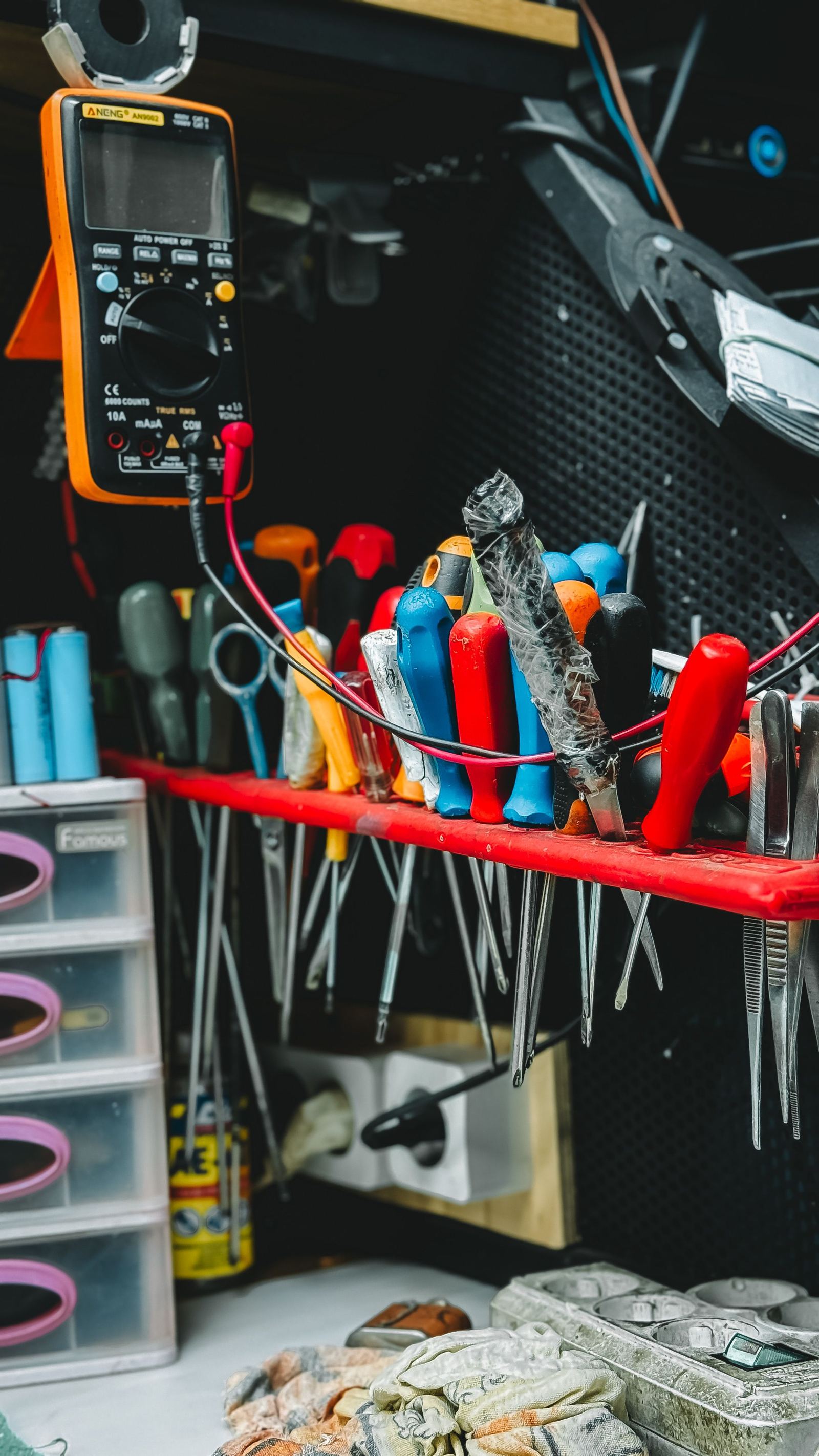 Multimeter, pliers and screwdrivers arranged on a workshop tool rack